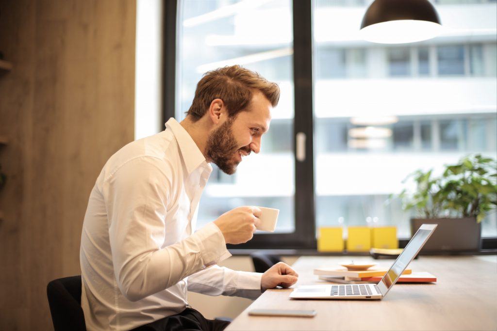 Businessman drinking coffee whilst working on a laptop